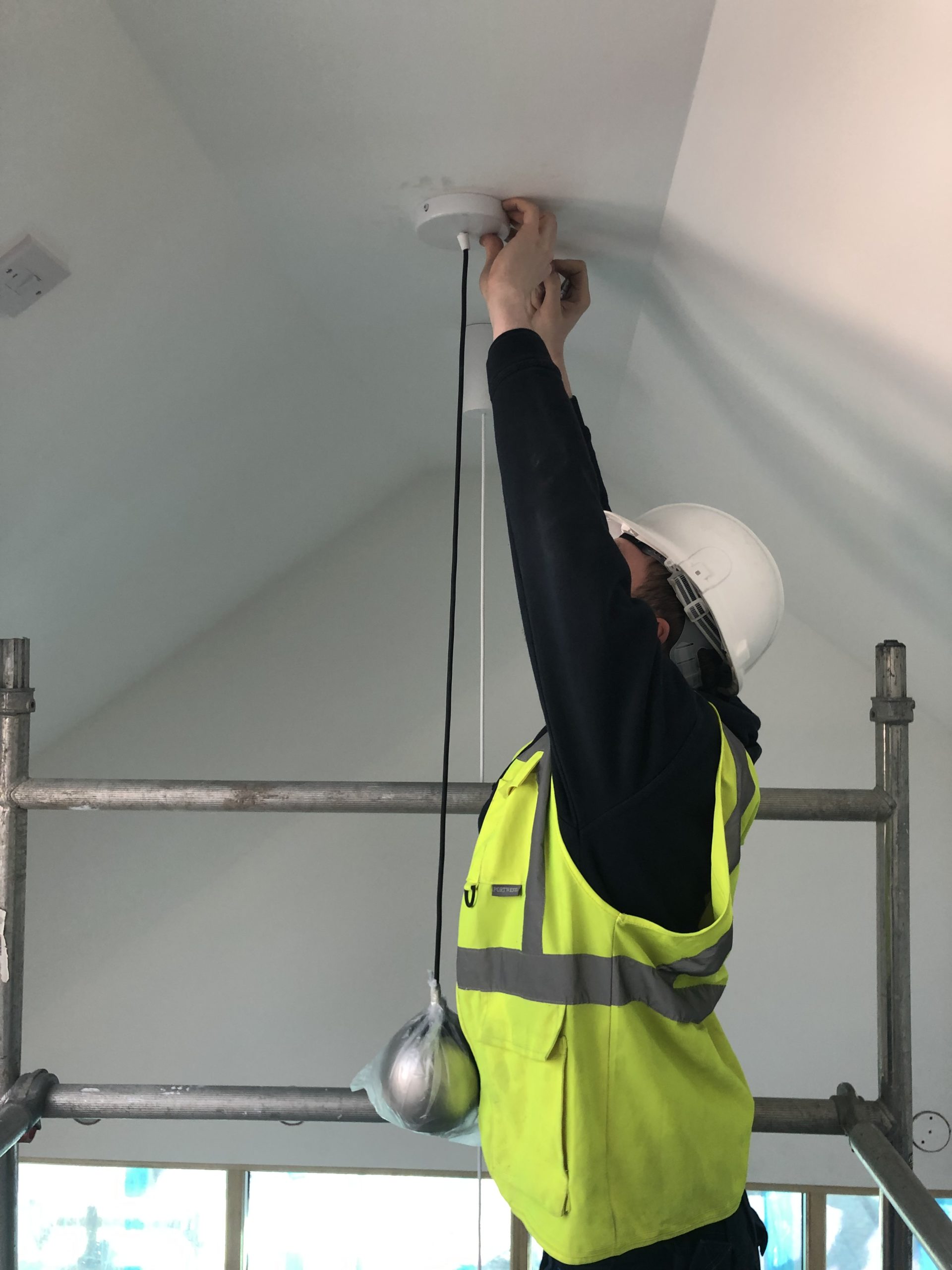 A Lairds engineer installing cabling at height in the hall at Ochiltree Community Hub A Lairds engineer installing cabling at height in the hall at Ochiltree Community Hub