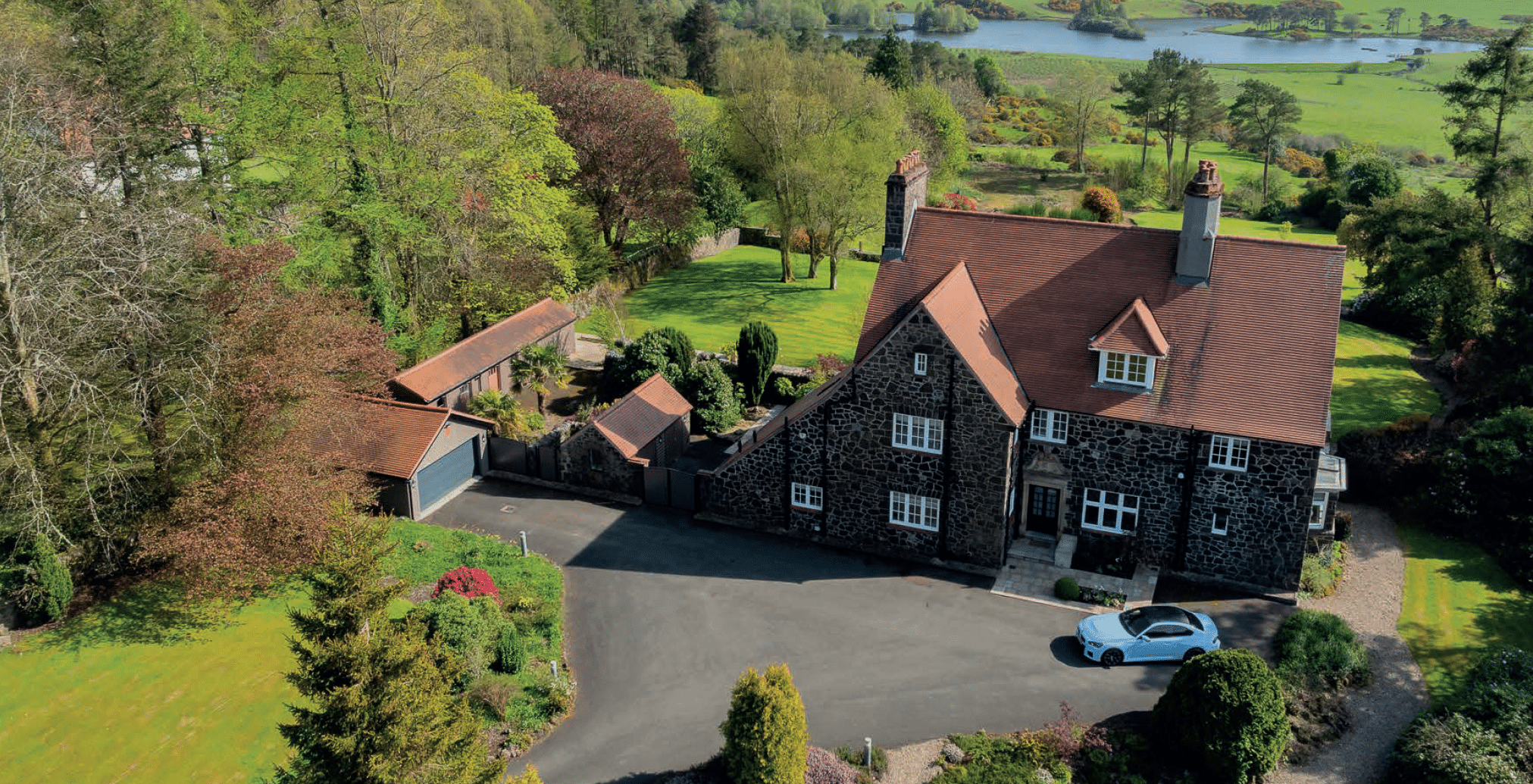 Greystones, Kilmacolm, from the air, a B-listed Arts and Crafts house above Knapps Loch